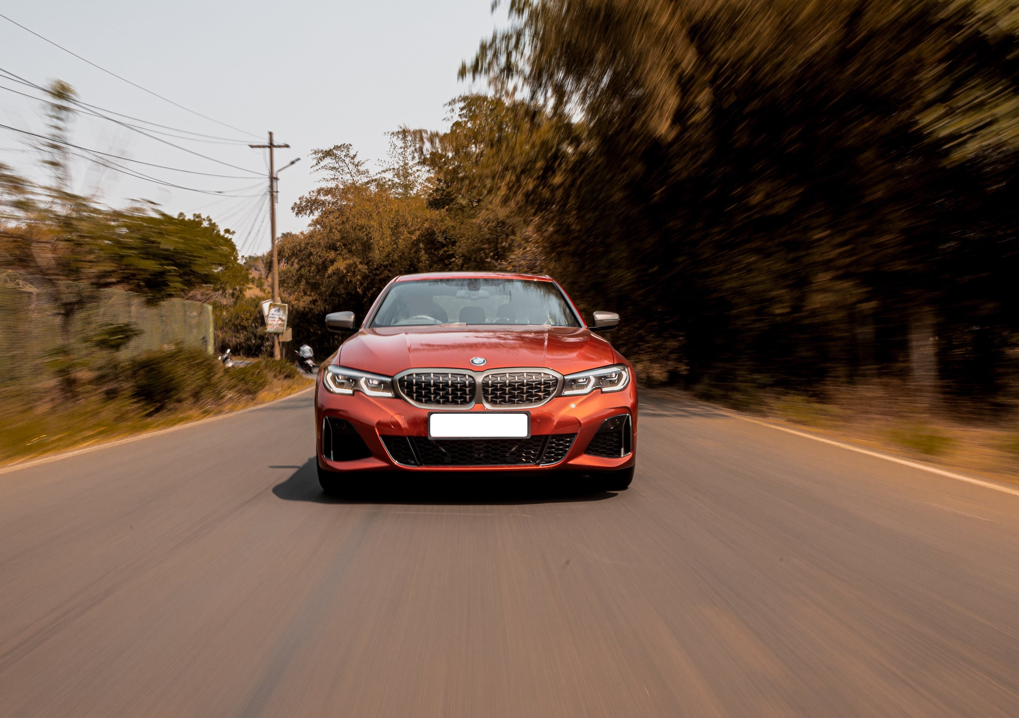 Red BMW driving on a scenic road, showcasing speed and performance with a blurred background.