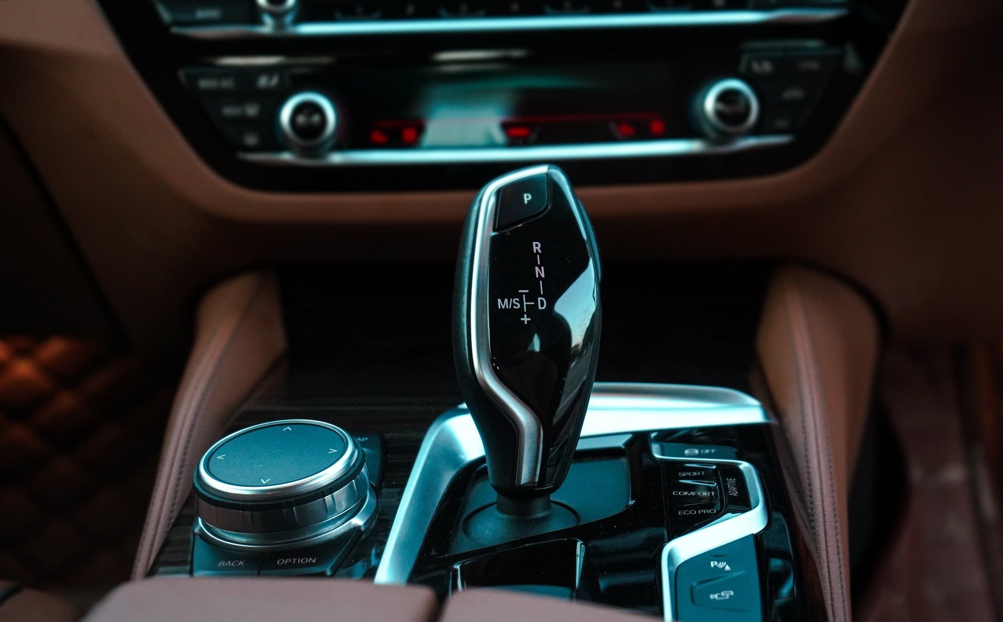 Close-up of a car's gear shift lever, showcasing drive modes and luxury interior features.